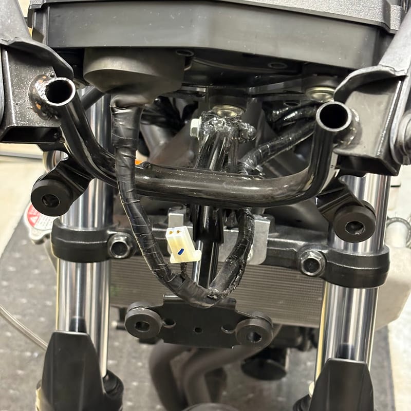 フロントカウリングとヘッドライトAss'yを外した車体の正面。メーターの下、カウルステーの奥にポジションランプの白い2極カプラーが下がっている