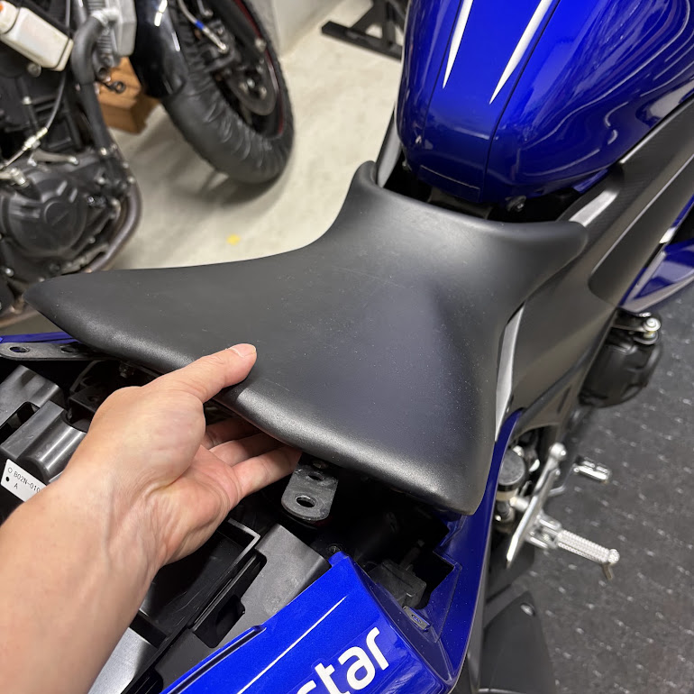 ライダーシートを手で持ち上げて外しているところ