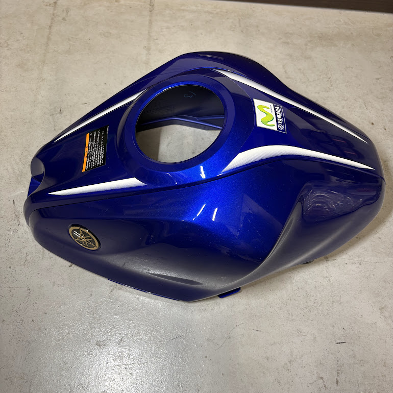 外したフューエルタンクカバー単体を表側から。MotoGPカラーのストライプとヤマハのロゴが見える