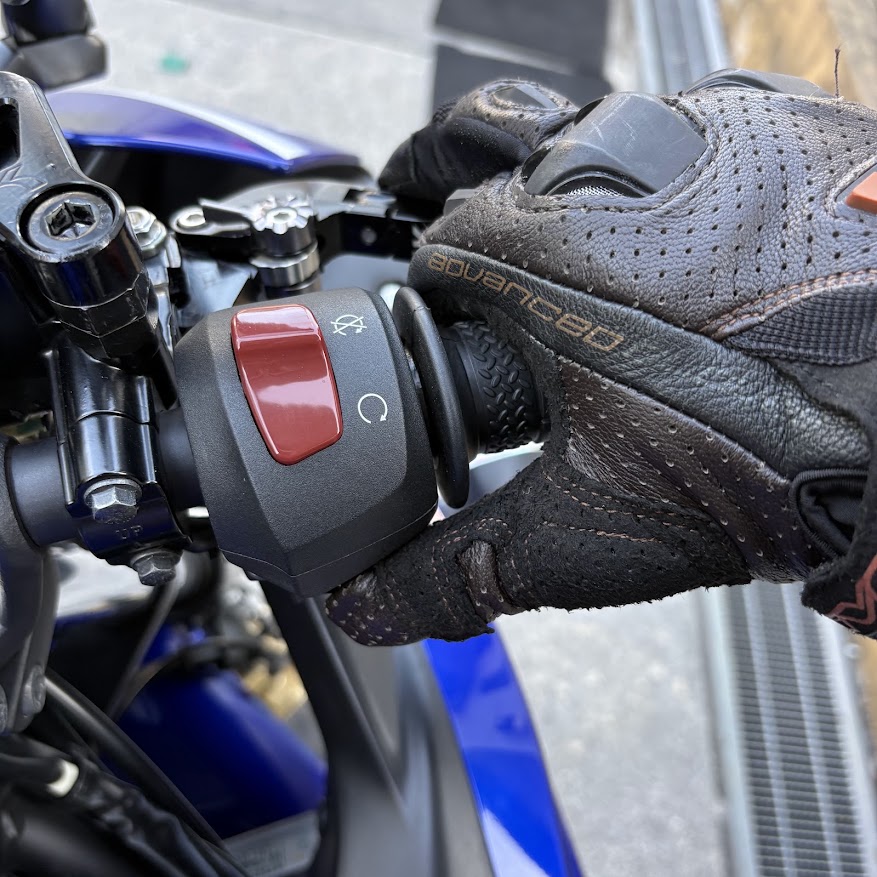YZF-R3の右ハンドル。グローブをはめた手がスロットルを少し開けながらスタータースイッチを押している
