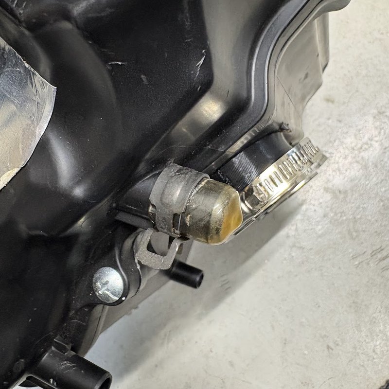 車体から外したエアクリーナーボックス。側面のニップルにキャップを被せ、ホースバンドで締めてある