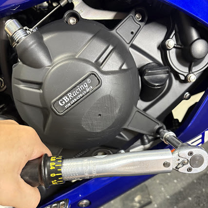 GB Racingのクラッチカバーを締め付けているところ。カバー下部に転倒による削れが見える