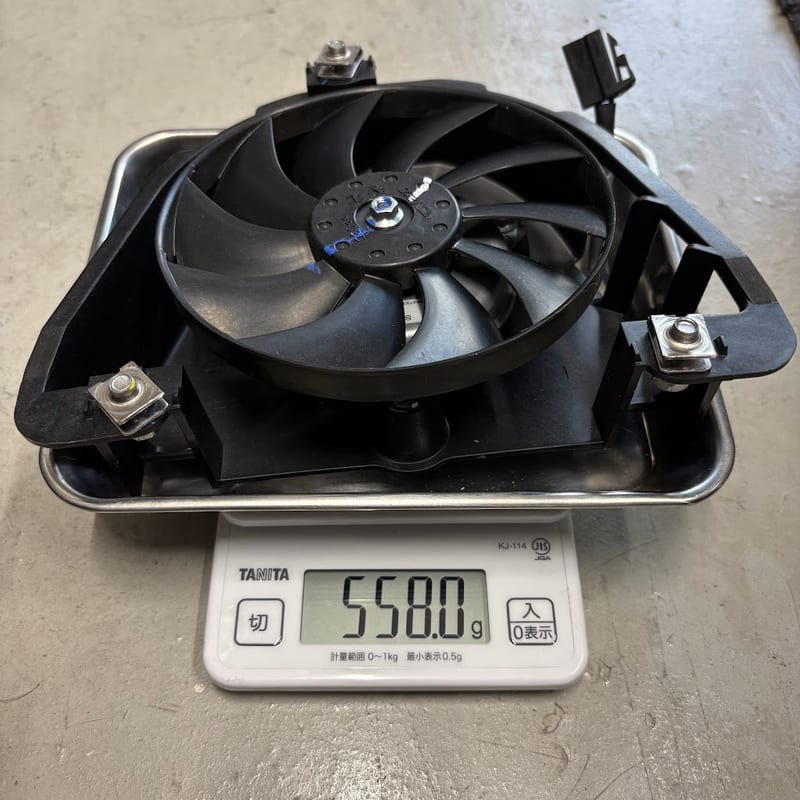 外したラジエターファンをキッチンスケールに載せたところ。表示は 558.0g