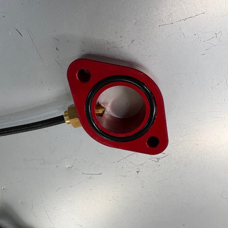 赤いサーモスタットキャンセルを上から見たところ。O リングがはまり、側面のポートに水温センサーがねじ込まれている