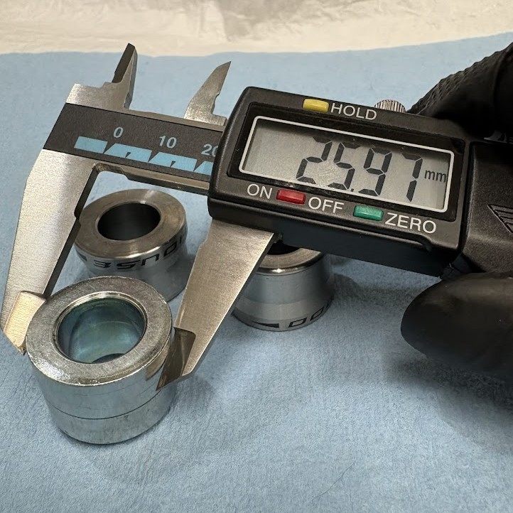 純正フロントアクスルカラーの当たり面の外径をノギスで測っているところ。25.97mm