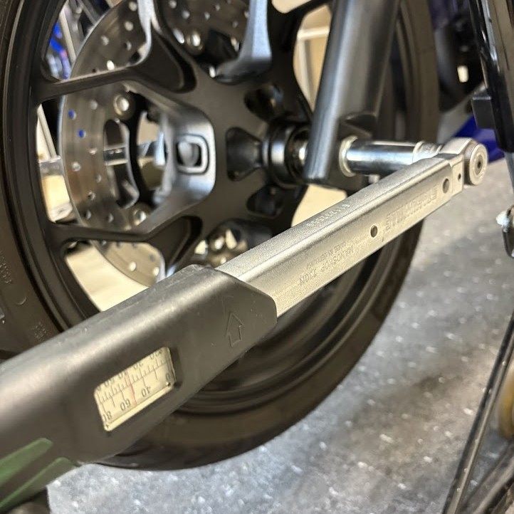 設定目盛りのあるトルクレンチで、YZF-R3のフロントアクスルナットを締めているところ