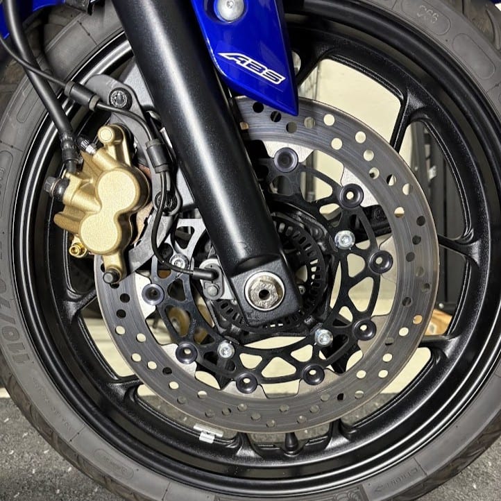 交換後のYZF-R3フロント周りを側面から。金色の純正キャリパーとサンスターのフローティングディスクローター。フローティングピンが黒色