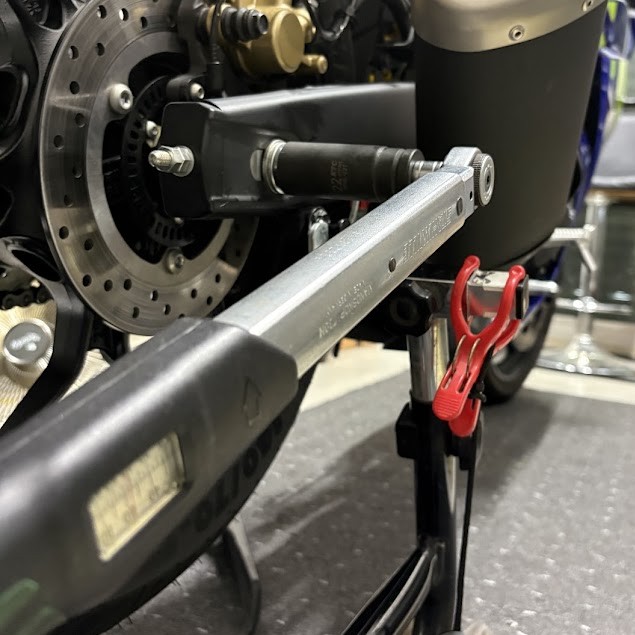 設定目盛りのあるトルクレンチで、YZF-R3のリアアクスルナットを締めているところ