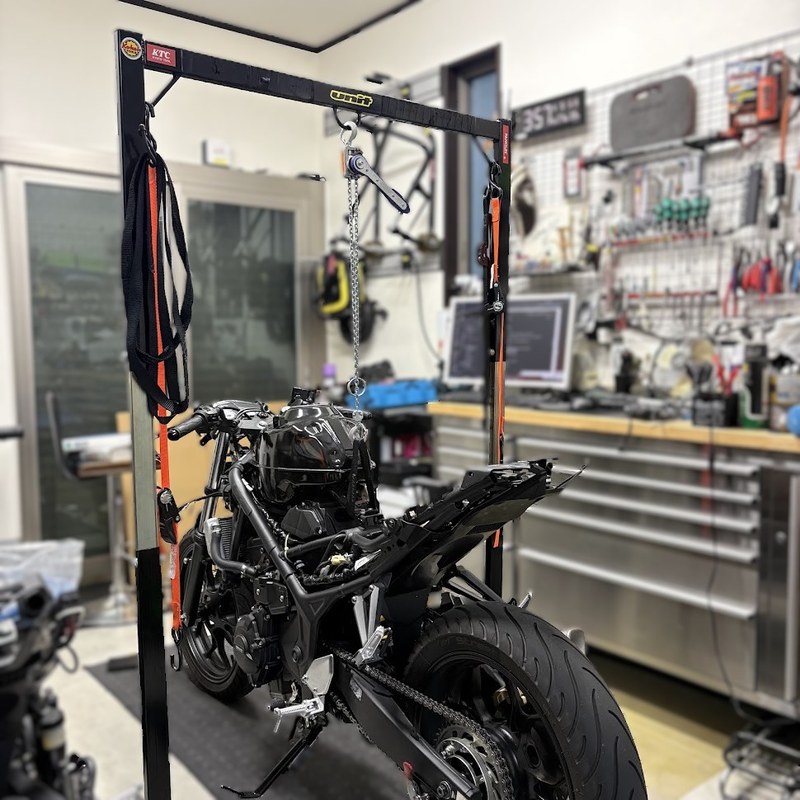 UNITのフレームスタンドをYZF-R3にまたがせ、上のビームからチェーンブロックを吊り下げた状態を前方から