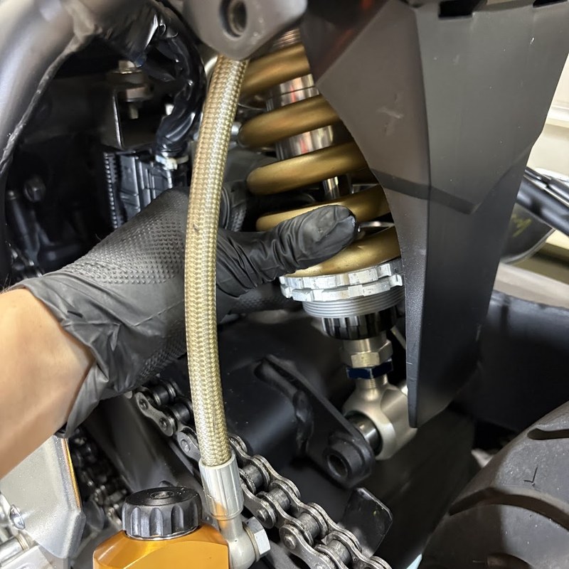 OHLINSのリアショックアブソーバーを上から車体に差し込み、手で支えているところ。下側のロッドエンドはまだ固定されていない