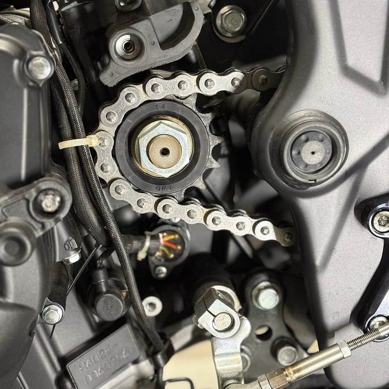 カバーを外したYZF-R3のドライブスプロケット。14の刻印とDIDのチェーン、左側を通る配線とギアポジションセンサーのコネクター