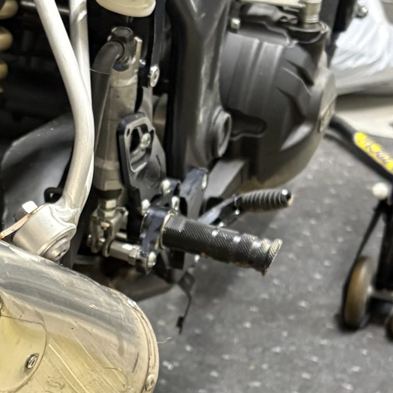 YZF-R25に装着されたままの右側ステップバー。先端が斜めに削れ落ちてエンドキャップが失われている
