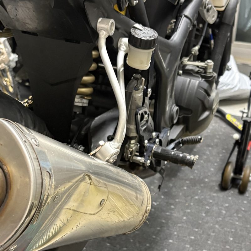 YZF-R25の右側。汎用のアルミステー2本でサイレンサーを吊り、タンデムステップブラケットが付いていない状態