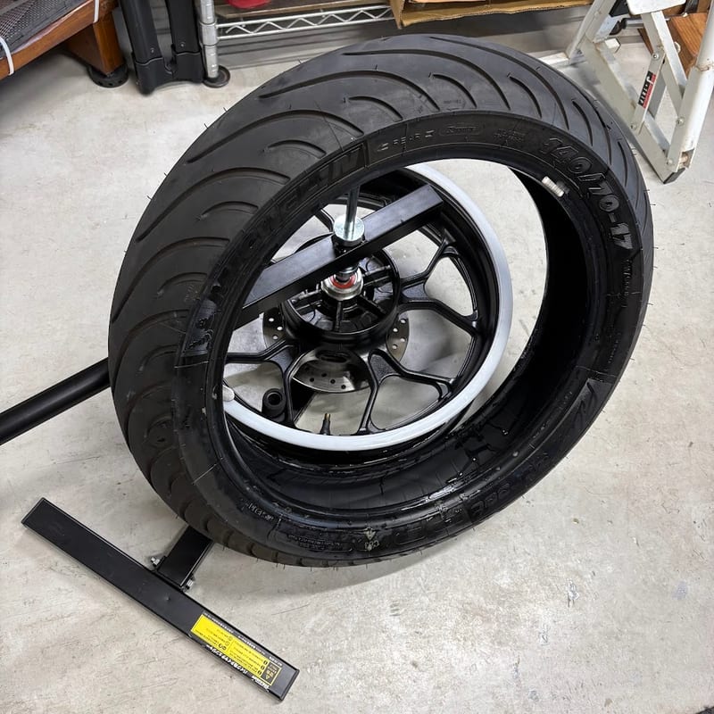 タイヤチェンジャーに載せたYZF-R3のリアホイールから、純正タイヤを外しているところ。リムに白いホイールプロテクター