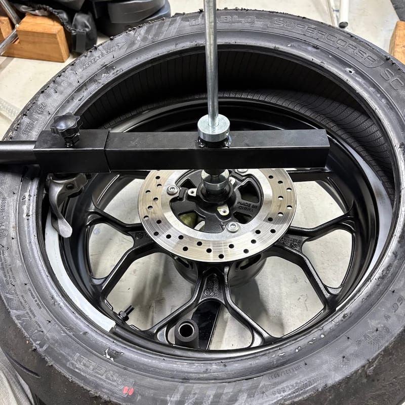 タイヤチェンジャーに載せたYZF-R3のリアホイールに、スーパーコルサ V4を重ねたところ。赤いマークがある面とブレーキディスクが上