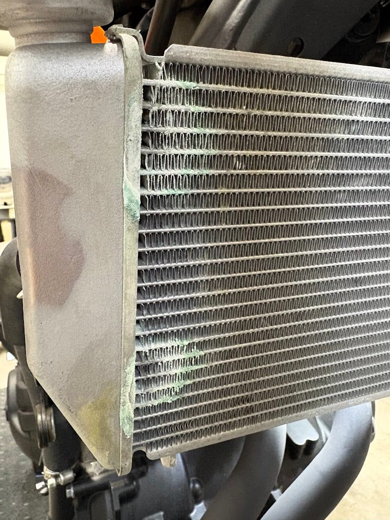 車体に付いたままの YZF-R3 のラジエター。タンクとコアの継ぎ目に沿って、緑がかった白い粉のようなものが上から下まで付いている