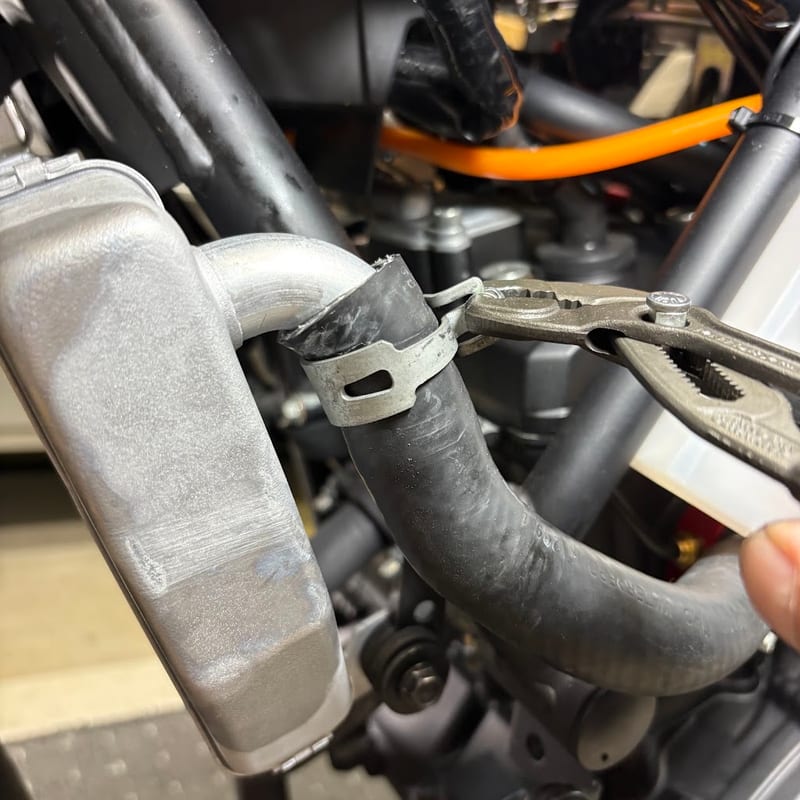 新品のラジエターのパイプに差したホースのクリップを、KNIPEX のホースクリップ用プライヤーで戻しているところ