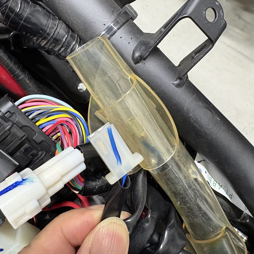 リアフェンダーを外したあと、車体側のハーネスに残るナンバー灯の白い2極カプラー。青い合いマークが入っている