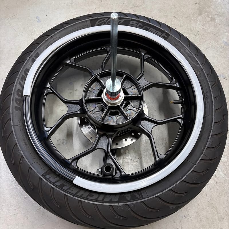 タイヤチェンジャーのシャフトに通したYZF-R3のリアホイール。リムに白いホイールプロテクター
